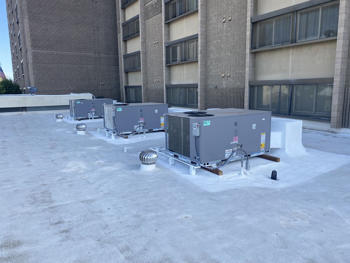 Row of commercial rooftop HVAC units on a multi-story building